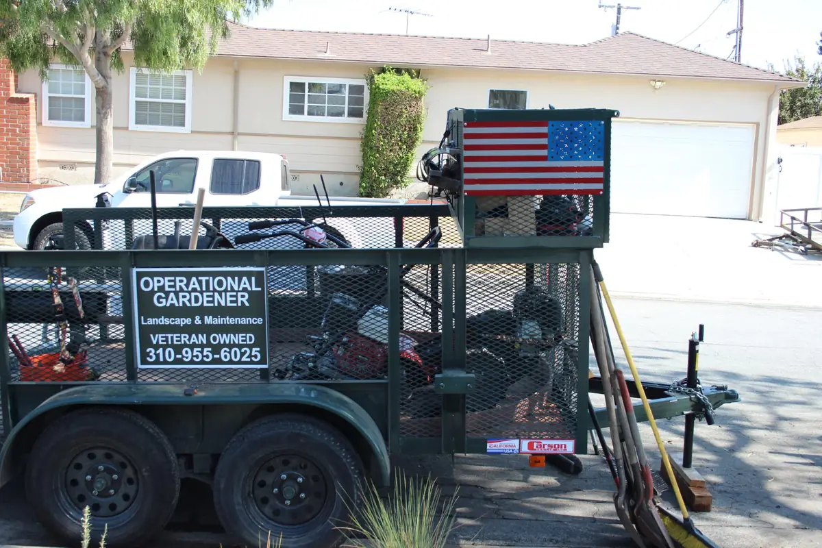 Operational Gardener veteran-owned landscape and maintenance trailer with hand-painted American flag panel and equipment loaded — veteran-owned landscaping in Torrance, Southern California