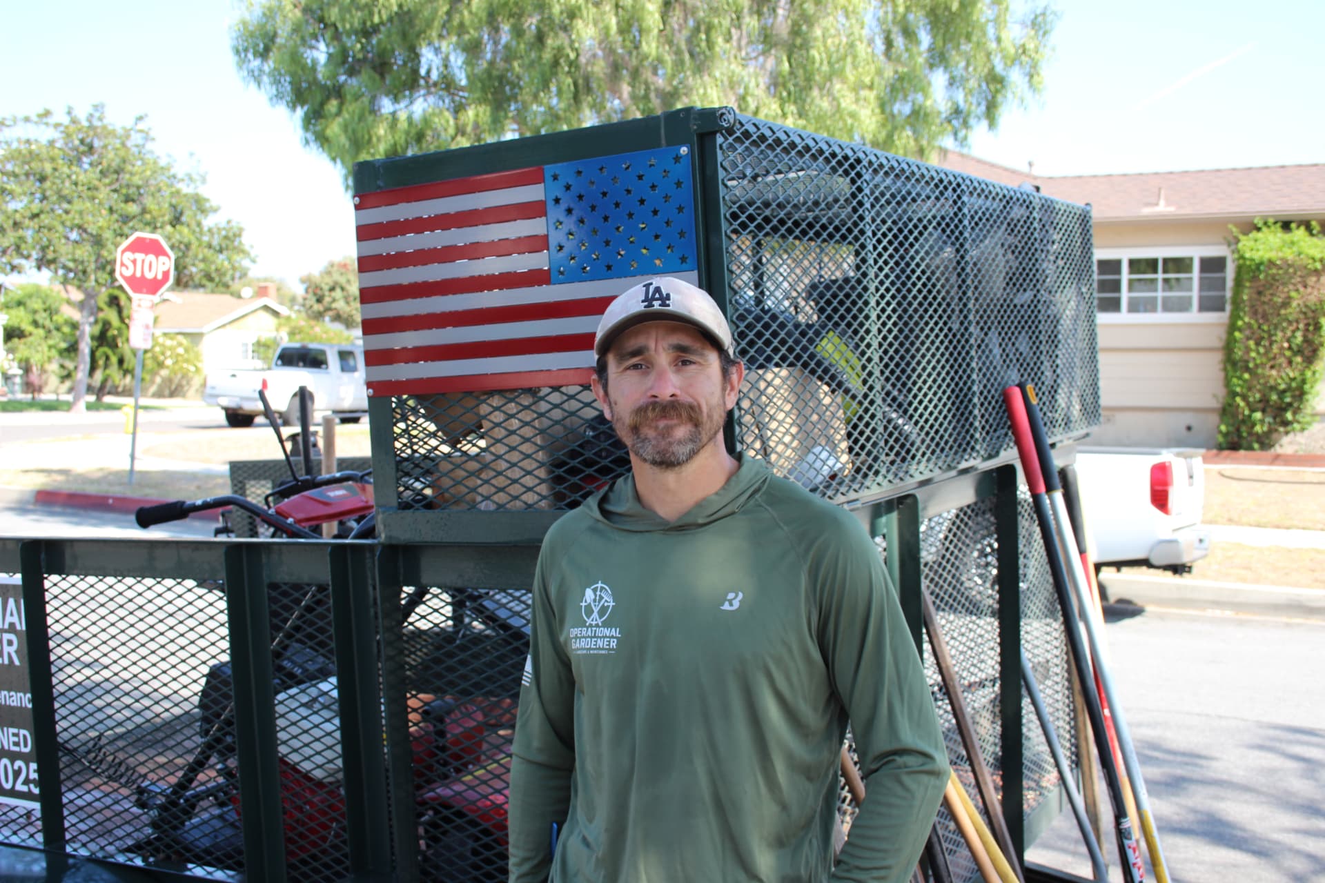 Founder standing in front of the Operational Gardener trailer with a steel American flag panel