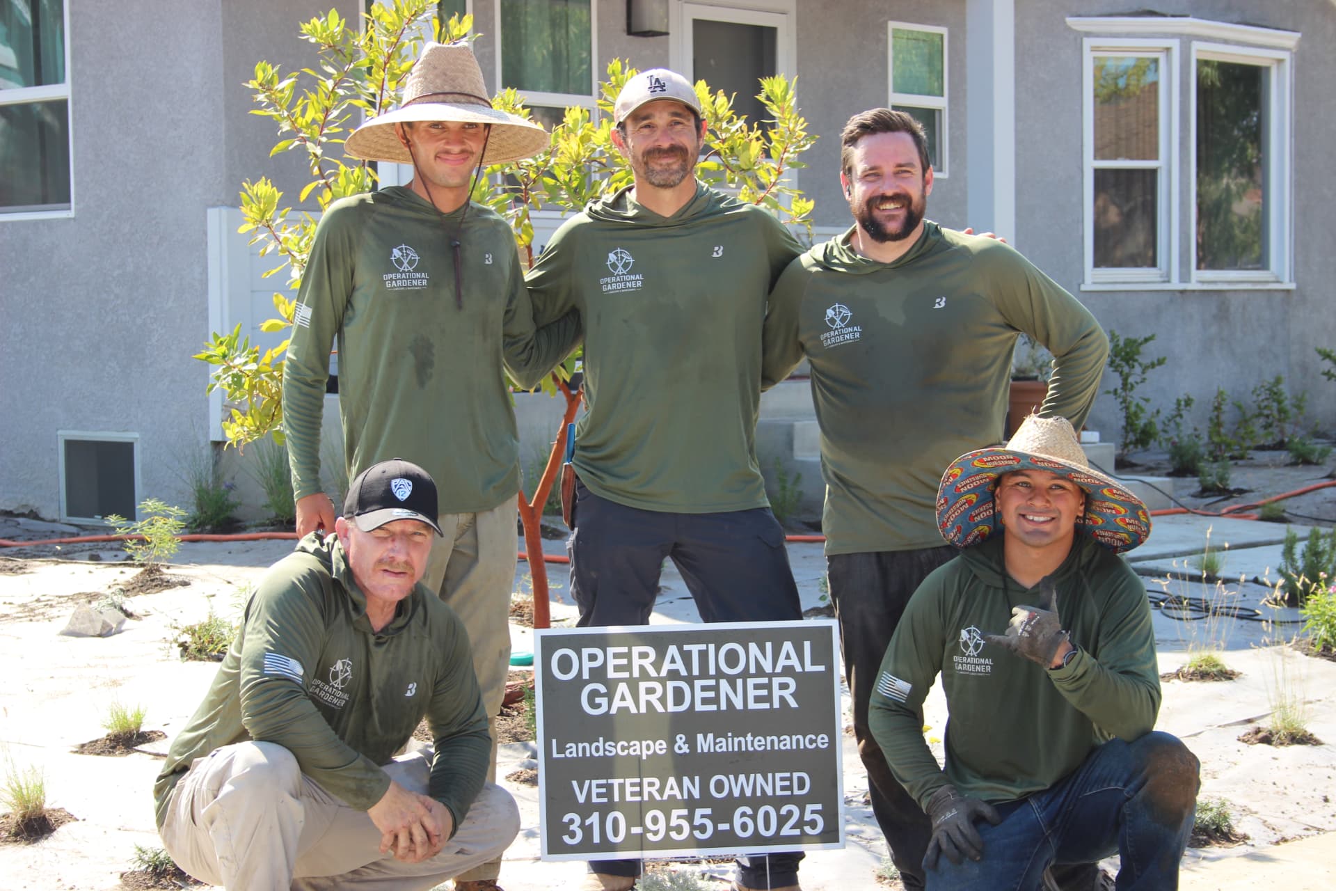 The Operational Gardener crew behind their veteran-owned landscape and maintenance sign